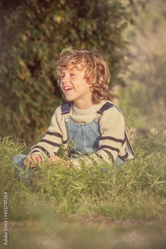 Little smiling boy sitting on grass