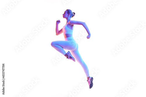 Side view portrait of young sporty woman running in action isolated against white background in neon light. © Lustre