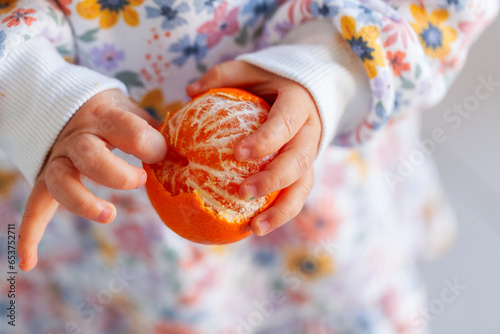 Child peeling skins off mandarin citrus fruit photo
