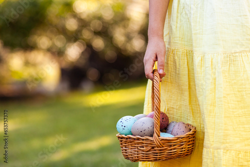 Close up of child holding wooden basket of speckled Easter eggs with copy space