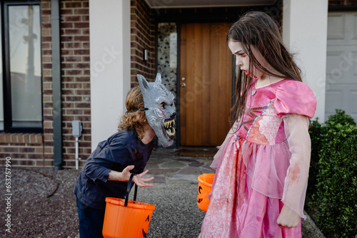 Two children dressed up for Halloween ready to trick or treat; a boy werewolf & vampire princess photo