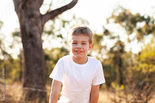 Smiling portrait of Australian boy in country setting with bokeh backdrop photo