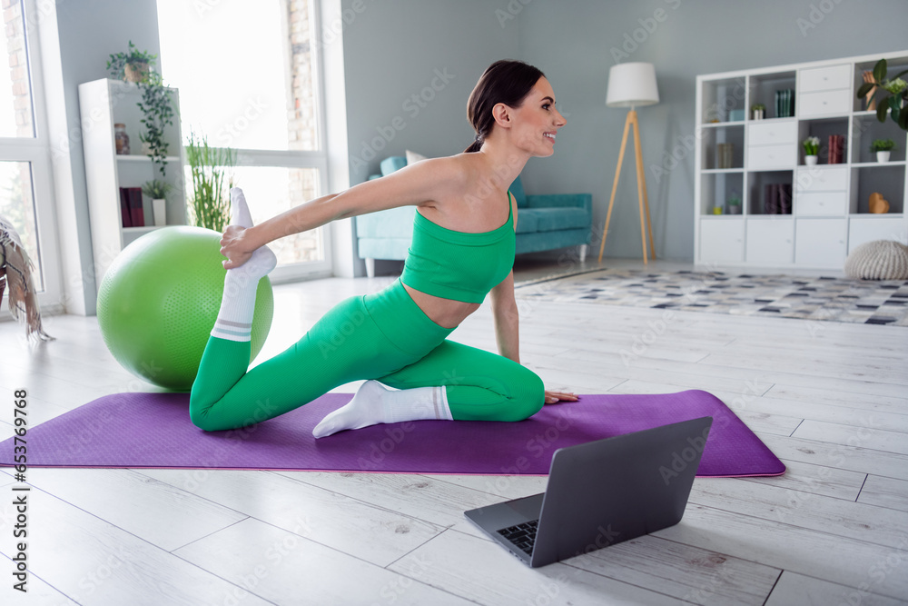 Photo of cheerful pretty girl dressed sportive suit watching internet class device stretching legs indoors house home Photo of cheerful pretty girl dressed sportive suit watching internet class device stretching legs indoors house home