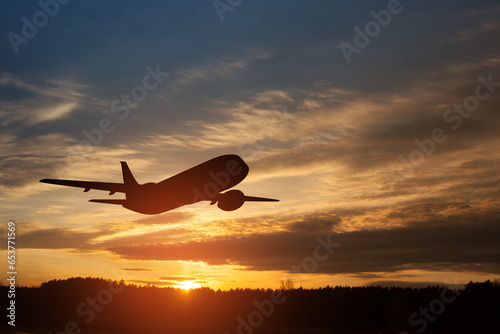 Airplane taking off at the sunset sky. Silhouette of aircraft in the sky.