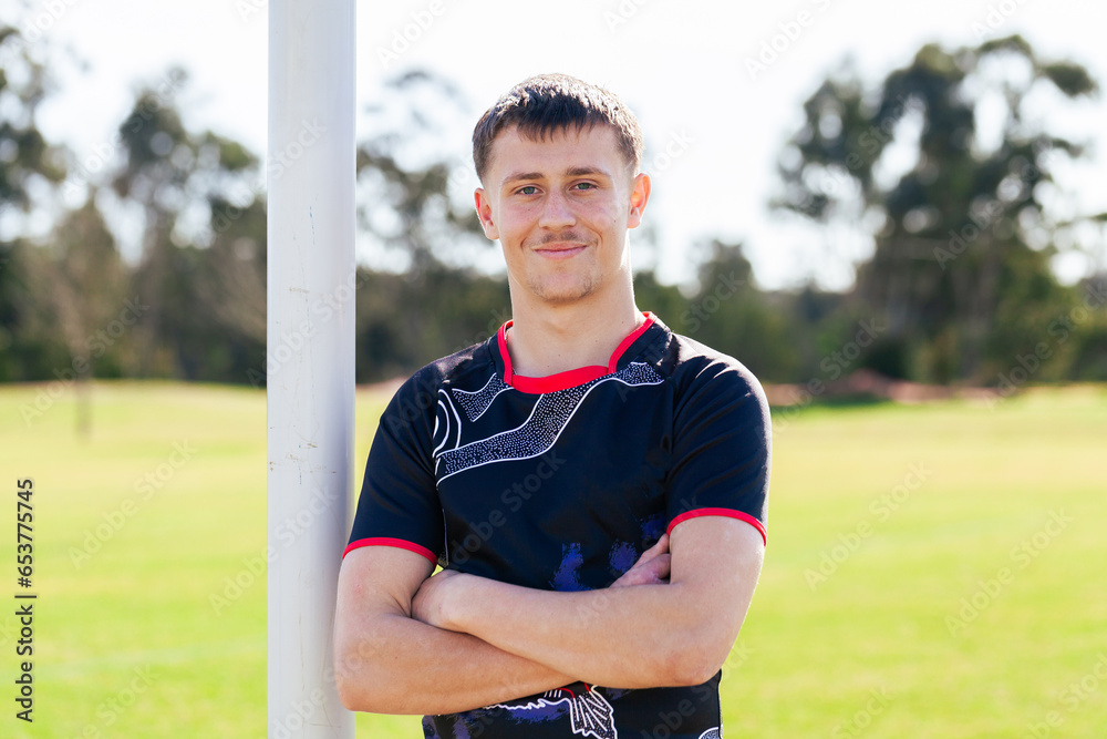 Smiling portrait of first nations sports person with arms folded leaning on goal post Smiling portrait of first nations sports person with arms folded leaning on goal post
