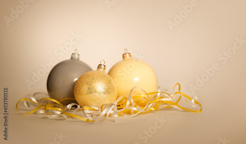 Wallpaper Mural Three Christmas New Year balls of gray gold and yellow lie near a serpentine on a yellow beige background. Torontodigital.ca