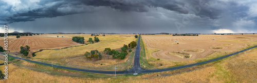 Heavy rain and dark cloud over dry farmland around a rural T intersection photo