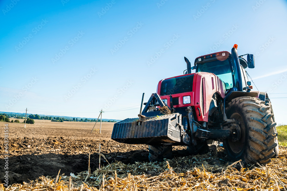 Obraz premium Tractor in the field. Agricultural machinery. Agricultural farm tractor during tillage of soil and field after harvest.