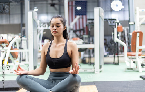 Beautiful young woman meditating yoga in fitness gym.