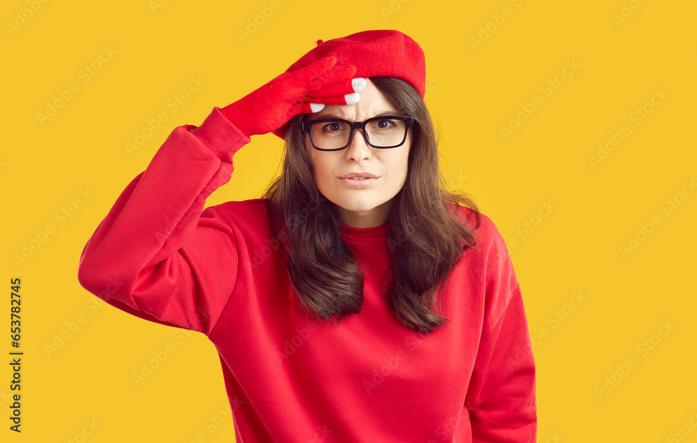 Are you serious. I don't understand. Incredible. Woman in red beret and eyeglasses puts hand at forehead and looks in distance with shocked perplexed sceptical troubled worried face expression. Studio