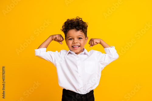 Photo of nice cool positive boy with curly hairdo dressed white shirt clenching fist scream yes isolated on yellow color background photo