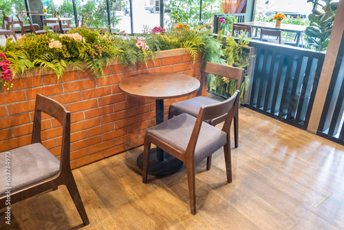 Wooden chairs and tables with green forest wall flower and red brick wall in Relax restaurant or cafe.