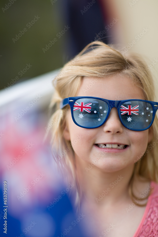 Child wearing Australia Day sunglasses waving Australian flag Child wearing Australia Day sunglasses waving Australian flag