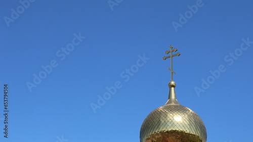 gilded dome of an orthodox church with a cross against a clear bright blue sky as a religious background with space for insertion, religious building exterior details, Christian culture element