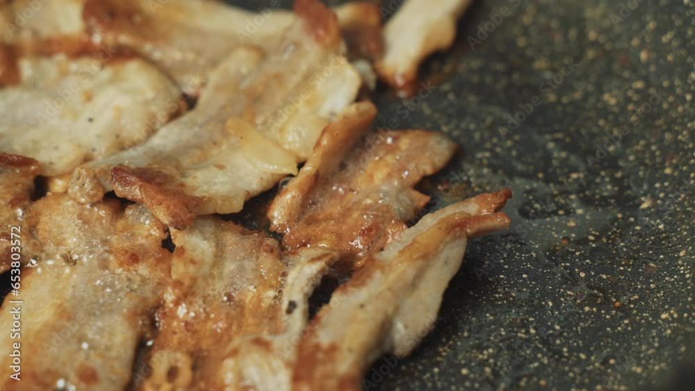 Bacon is fried in a frying pan in boiling fat. Harmful, unhealthy food