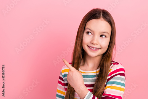Photo of cheerful toothy smile child indicating finger empty space positive advertisement introduction isolated on pink color background