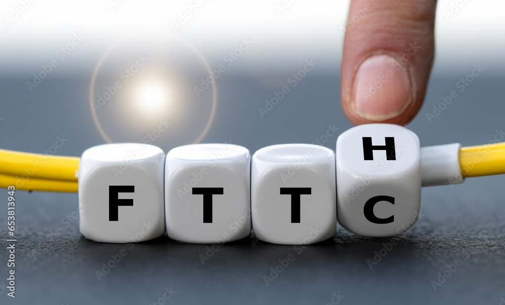 Hand turns dice and changes the expression Fiber to the curb (FTTC) to Fiber to the home (FTTH). Symbol for connecting residences directly with optical fibers. - obrazy, fototapety, plakaty 