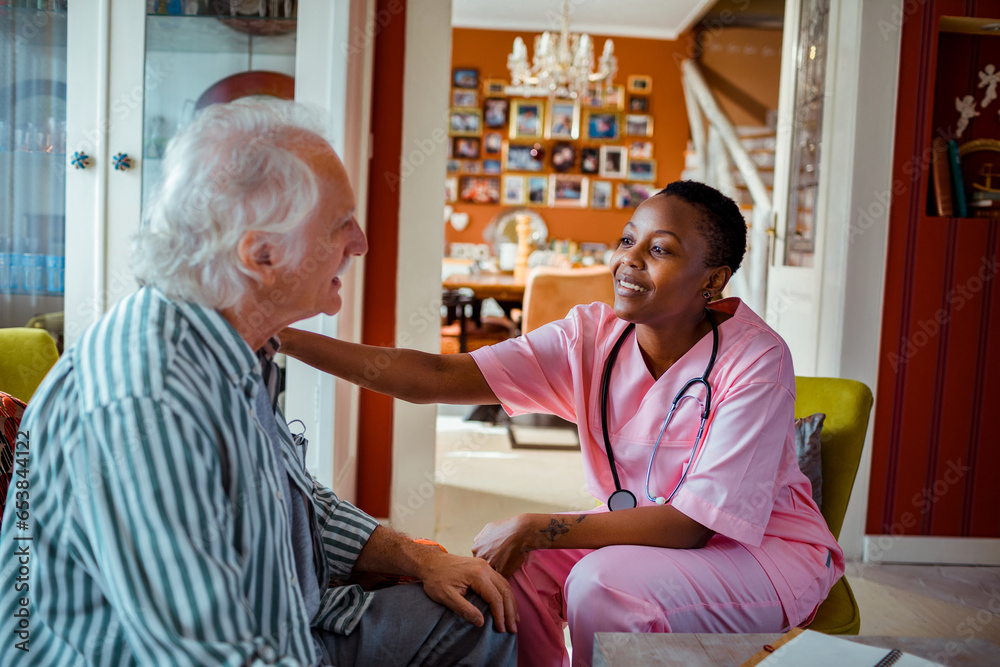 © Marko Geber - Young African American female caregiver consulting her senior patient at home