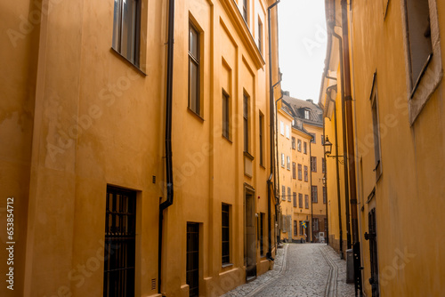 Medieval yellow stone houses in urban historic narrow alley in Stockholm Old Town Gamla Stan by Bollhusgränd street in bright summer day