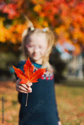 girl holding a red maple leaf during autumn evening in Toronto