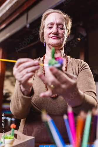 Artista senior feliz pintando um vaso de ceramica. photo