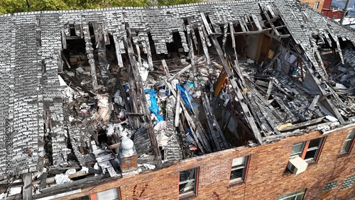 An aerial view of a collapsed roof on an old three-story red brick industrial building.  	