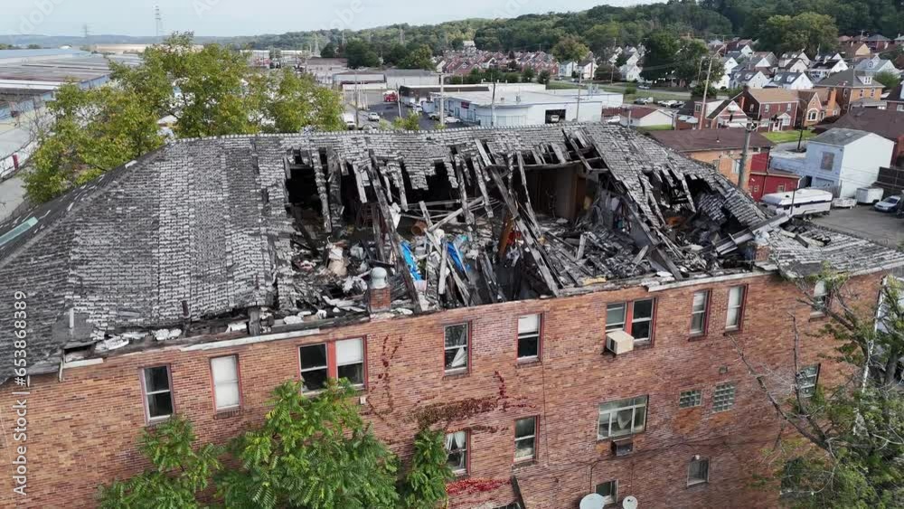 A slow aerial approach to an old abandoned building with a collapsed rooftop.  	