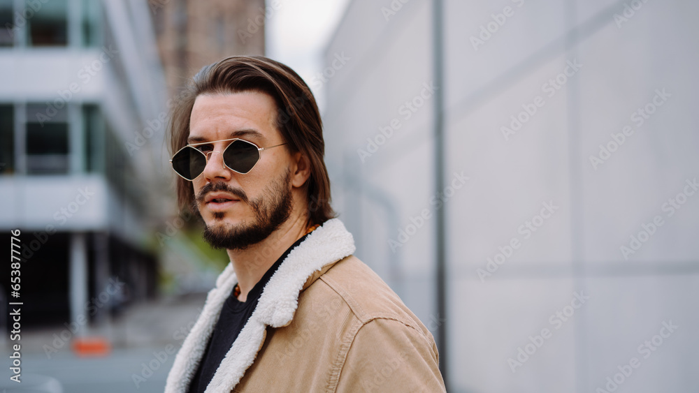 Portrait of young attractive man in casual clothes, wearing sunglasses and posing