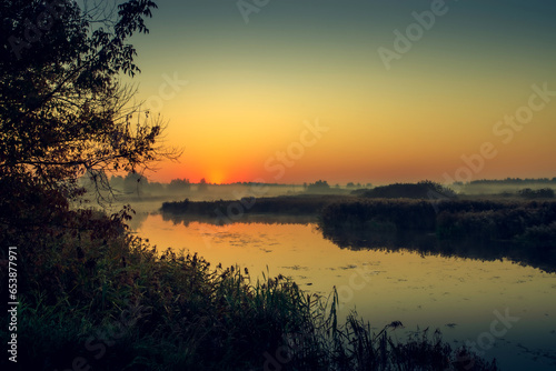 Morning fog on the lake, sunrise shot. Summer or autumn landscape.