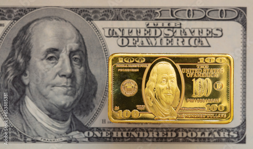 US 100 dollar golden bar die cut stamp on US 100 dollar banknote background photo