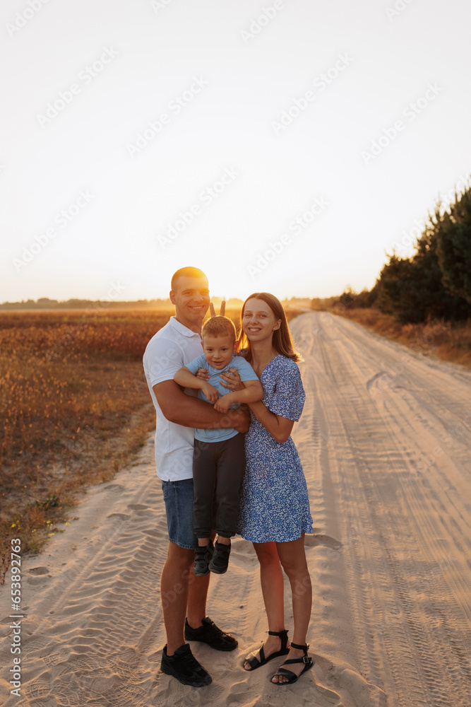 A man and a woman and a little son in a field at sunset. Family photos in the summer at sunset in the field A man and a woman and a little son in a field at sunset. Family photos in the summer at sunset in the field