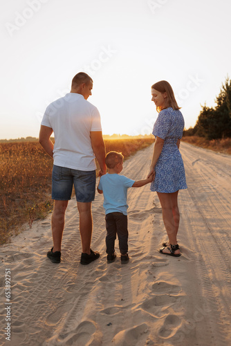 A man and a woman and a little son in a field at sunset. Family photos in the summer at sunset in the field