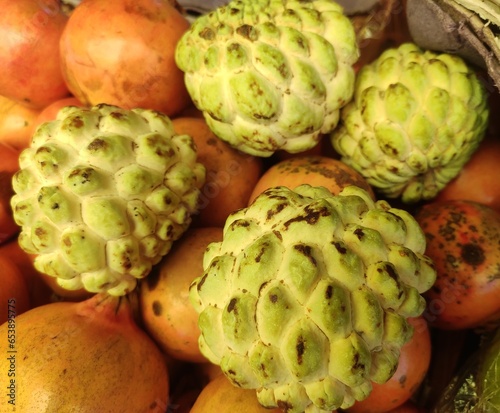 Sugar apple or sweetsop is a fruit of the plant Annona squamosa. The round or heart-shaped greenish yellow, ripened aggregate fruit is pendulous on a thickened stalk. 