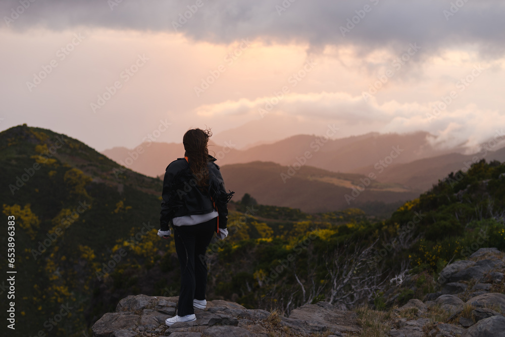 Travelling and exploring Madeira island landscapes and travel destinations. Young female tourist enjoying the sunrise and outdoor spectacular scenery. Summer tourism by Atlantic ocean and mountains.