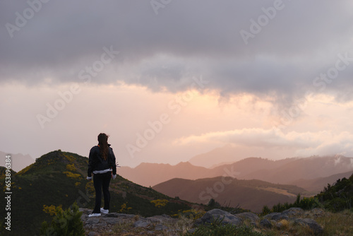 Travelling and exploring Madeira island landscapes and travel destinations. Young female tourist enjoying the sunrise and outdoor spectacular scenery. Summer tourism by Atlantic ocean and mountains.