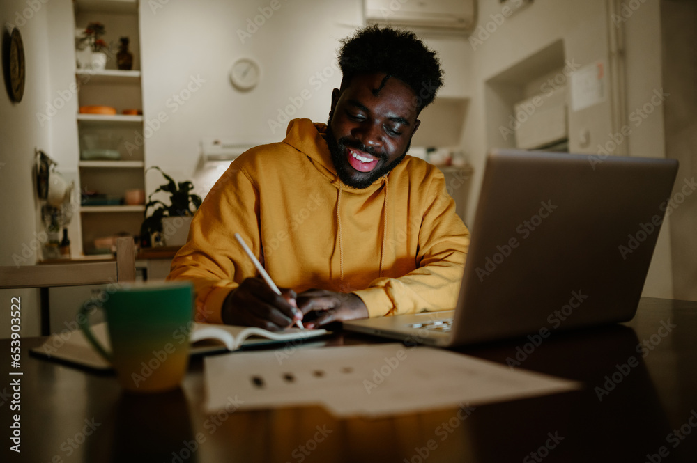 A happy african american remote worker is sitting at home late at night A happy african american remote worker is sitting at home late at night