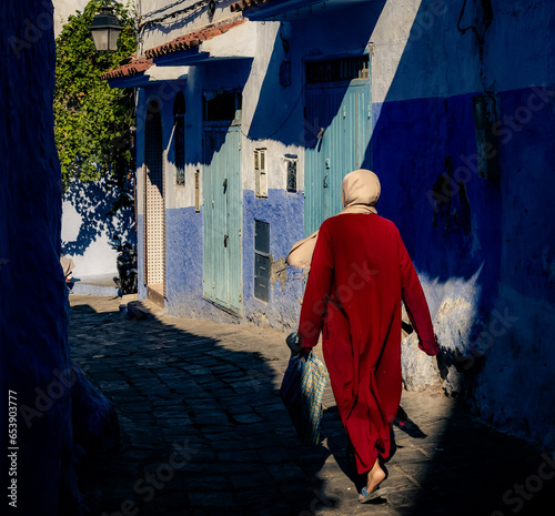  silhouette in traditional moroccan dress on the blue street of  Chefchaouen, Morocco, Africa © Agata Kadar