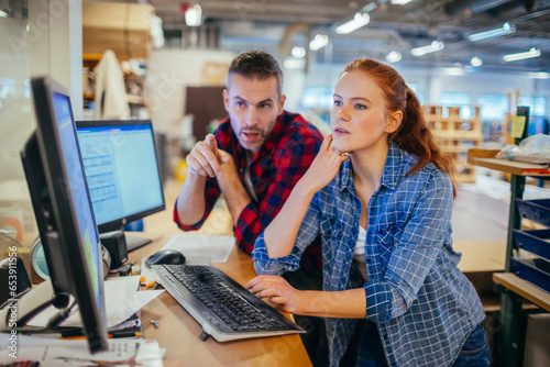 Foto Young man and woman using a computer while working in a printing press office