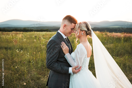 young couple in love holding each other, bride and groom during wedding photoshoot, shot of newlyweds in the middle of a sun-covered field, beautiful bride and stylish groom, love is here