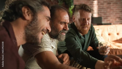Middle aged group of friends using a smartphone together while having drinks at home