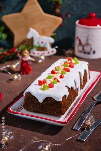 Dessert, Polish poppy seed cake with apples and candied fruits, covered with sugar icing, in Christmas style on a brown concrete background. Merry Christmas. Polish cuisine
