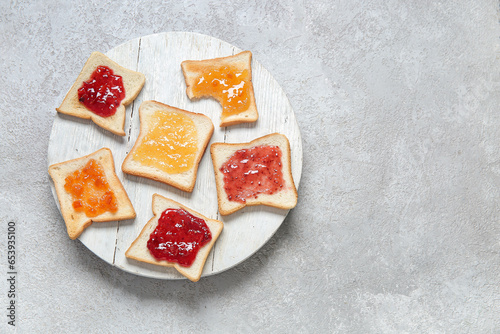 Plate of delicious toasts with different jams on grunge grey background
