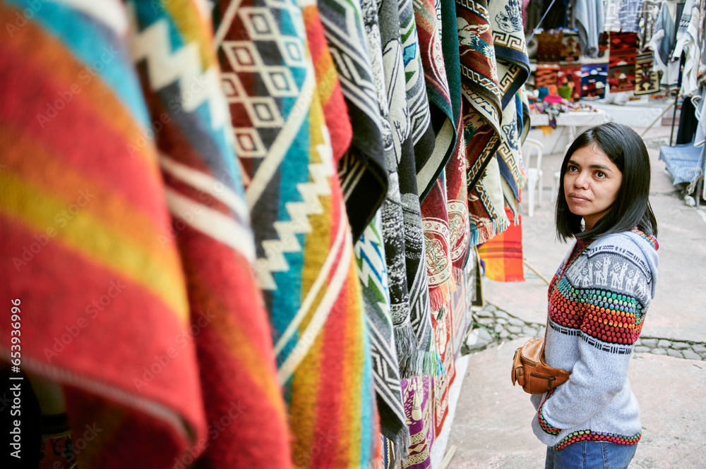 Woman looking at traditional market stall in Otavalo, Ecuador