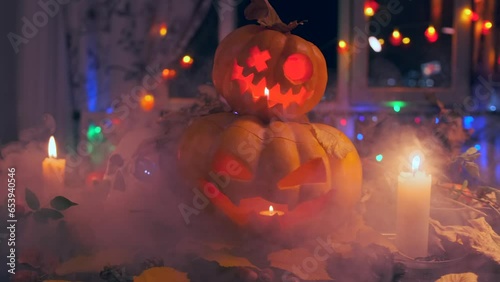 Jack-o'-lanterns glowing colorful lights on threshold of house in fog, decorated holiday backdrop flashing garlands and candles during Halloween holiday celebration slow tracking shot. photo