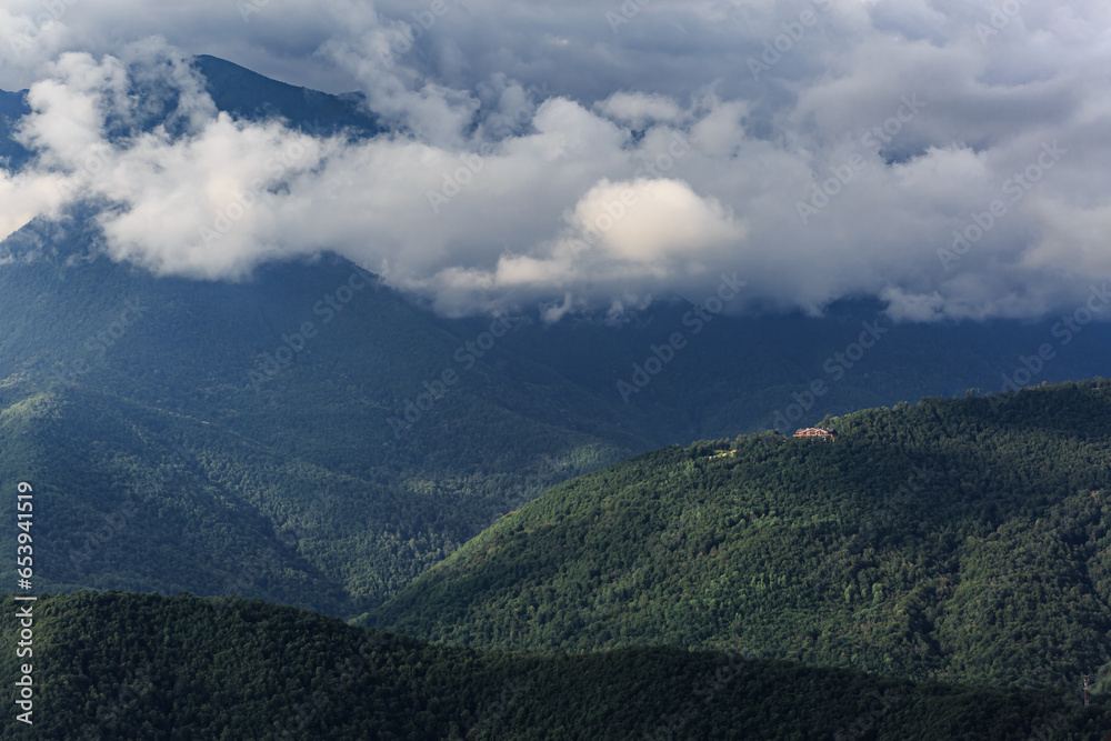 Green mountains, big clouds, a small house in the distance. Krasnaya Polyana. Green mountains, big clouds, a small house in the distance. Krasnaya Polyana.