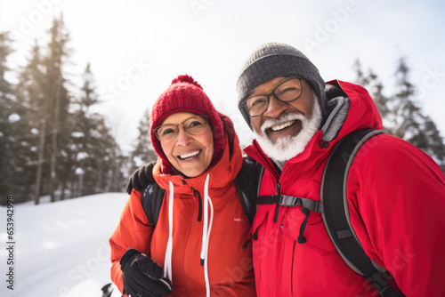 Happy adult couple in winter clothes walking in snowy forest.