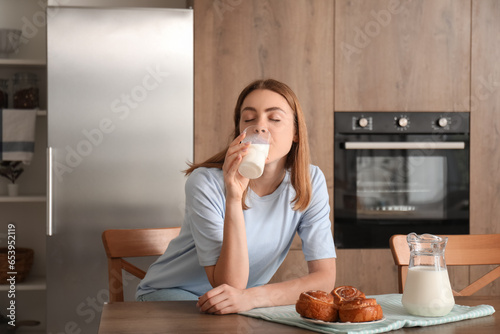 Fotografie Young woman drinking milk in kitchen