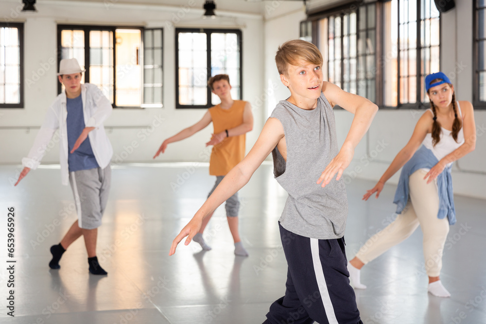 Teenager girl and boys exercising hip-hop dancing indoors