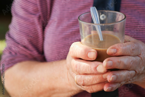 unrecognizable senior woman drinking coffee with milk