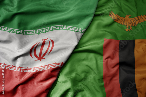 big waving realistic national colorful flag of iran and national flag of zambia .